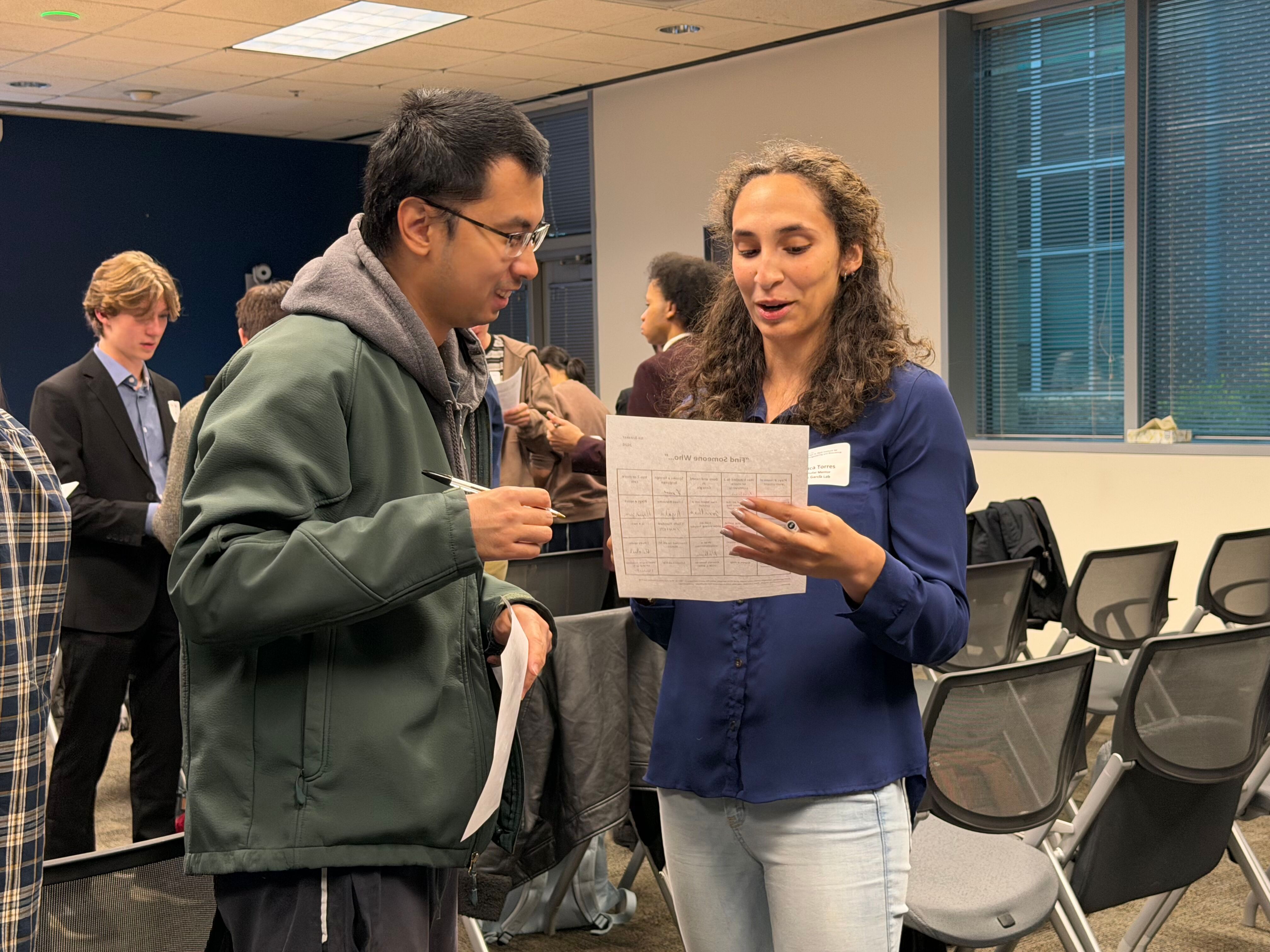 Two Petit Scholars mentors, a man and a woman, speak to each other and look at a shared piece of paper.