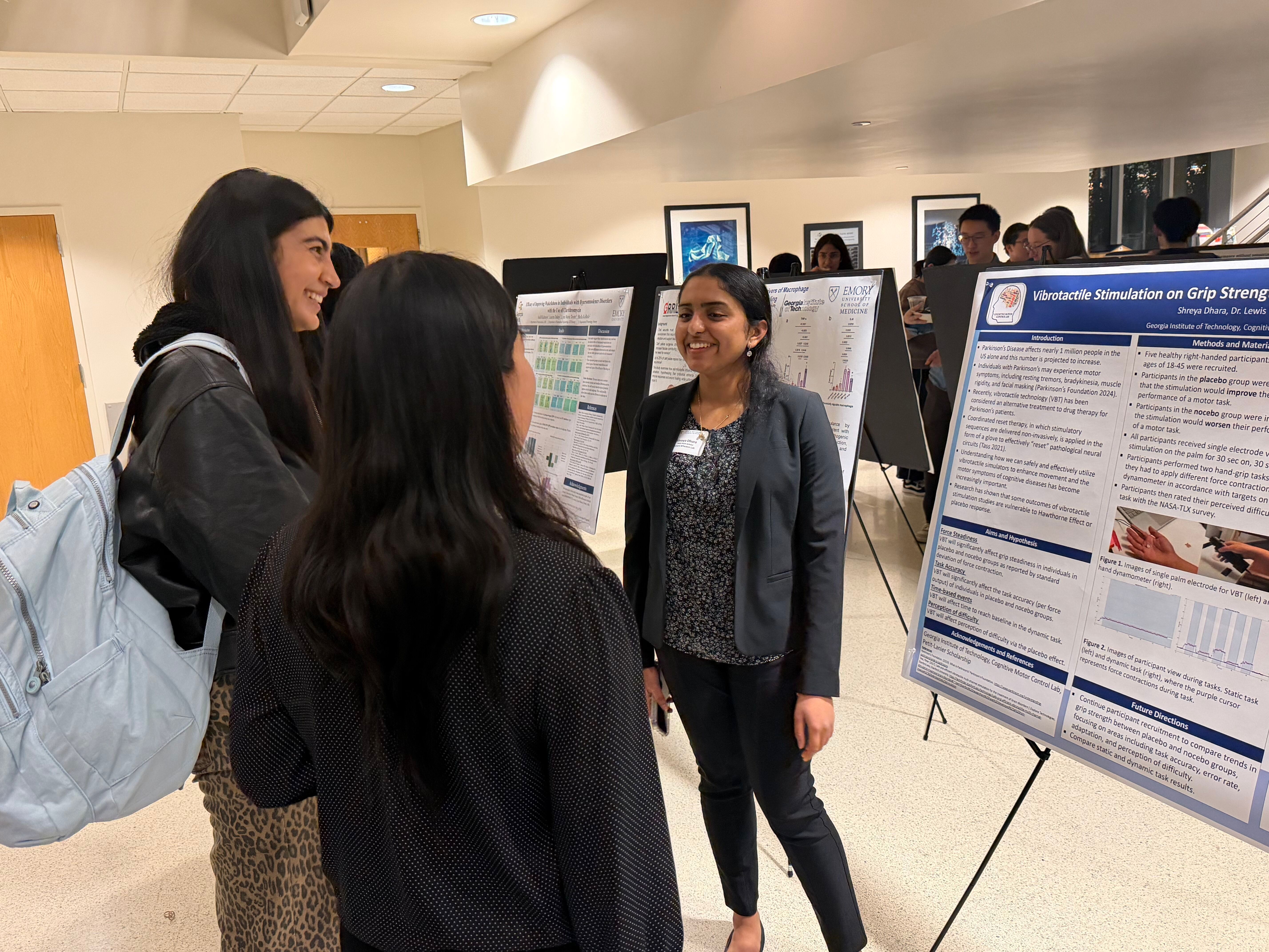 A group of Petit Scholars stand in front of a scientific poster and talk to each other while smiling.