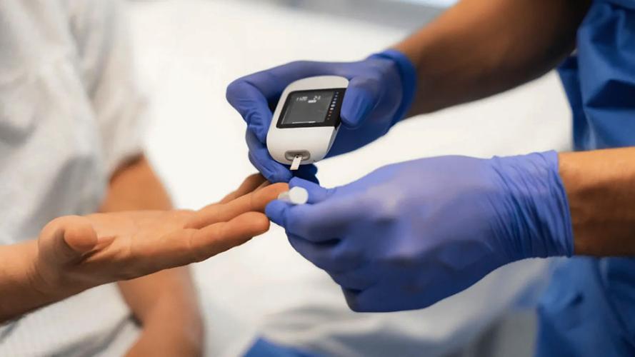A medical worker wearing latex gloves uses a device to test a patient's blood sugar.